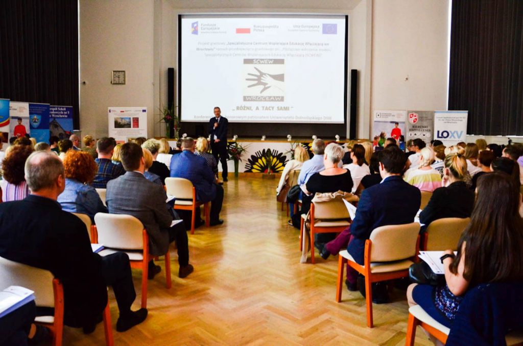 Zdjęcie przedstawia salę, w które siedzą na krzesełkach osoby na konferencji