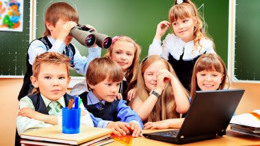 Szczęśliwi uczniowie w klasie patrząc przez lornetkę