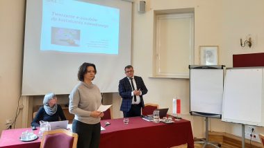 Na zdjęciu sala wykładowa. W tle ekran z widocznym napisem Tworzenie ezasobów do kształcenia zawodowego. Dyrektor ORE Tomasz Madej przemawia. Obok stoi kierownik projektu Tworzenie ezasobów do kształcenia zawodowego Joanna Saska-Dymnicka