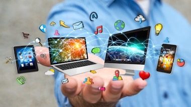 Zdjęcie dłoni, na której umiejscowiony jest laptop i monitor