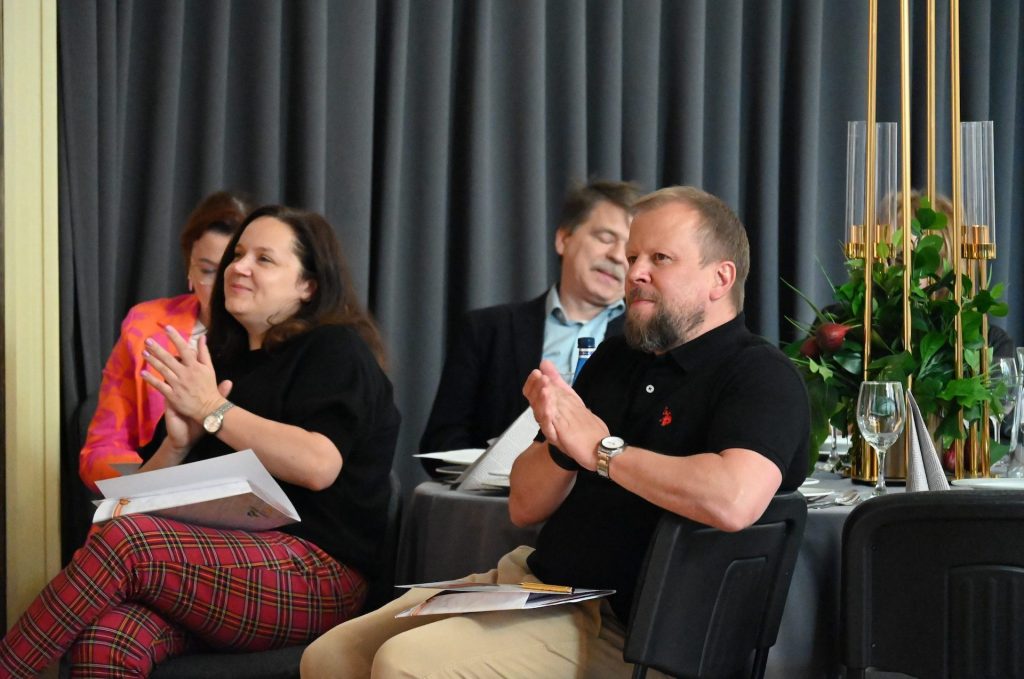 Zdjęcie przedstawia dwie osoby 4 osoby uczestniczące w konferencko, które klaszczą w ręce