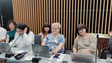 zdjęcie przedstawia siedem osób, które siedzą przy stołami z laptopami. Są to członkowie Centrum koordynującego