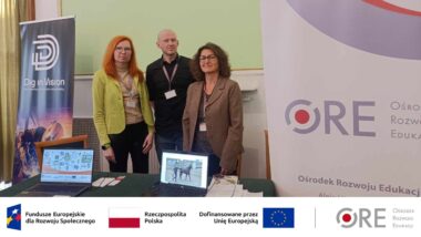 Przedstawiciele zespołu projektu: Katarzyna Lidia Kuklińska, Sebastian Dmochowski i Barbara Wałecka stoją przy stole. Na stole znajdują się ulotki Ośrodka Rozwoju Edukacji i ulotki projektu oraz dwa otwarte laptopy. Z prawej strony stołu stoi stojak reklamowy z napisem "ORE".